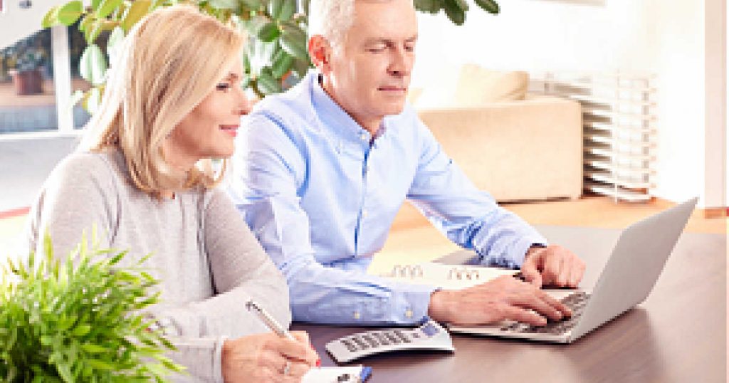 Shot of a middle aged couple sitting at home in front of laptop and manage their finances online.