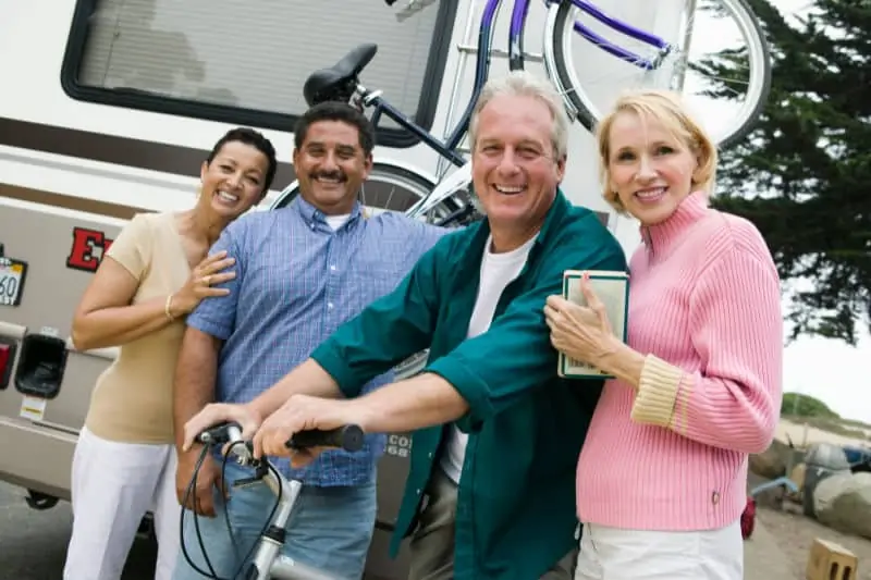 Two middle-aged couples standing beside RV