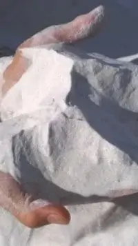 a pair of hands holding white sand