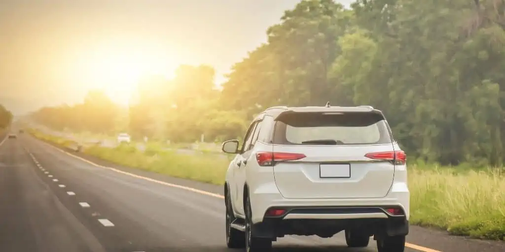 white suv on highway heading towards the sun