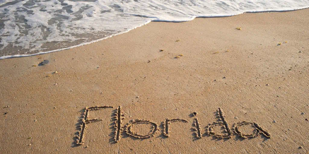 florida written in beach sand near ocean water