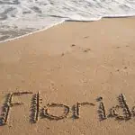 florida written in beach sand near ocean water